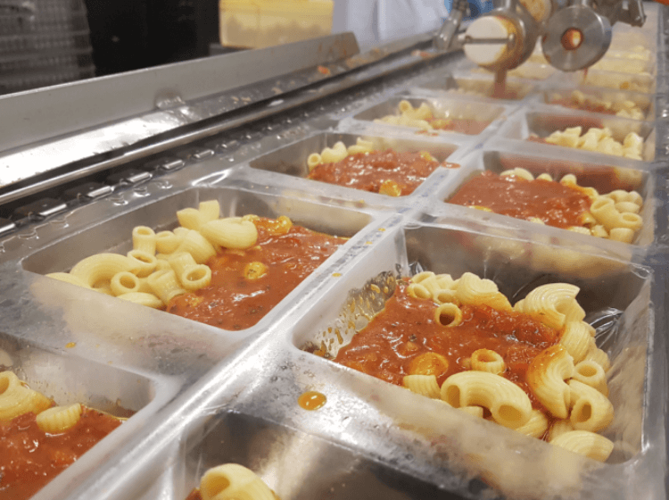 Image of pasta in trays in food production factory.