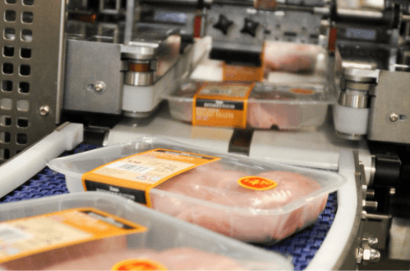 Image of chicken portioned and packaged and on a conveyer belt in Faccenda foods factory.